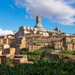 Photograph of the town of Cosa Vedere with bright blue sky and clouds